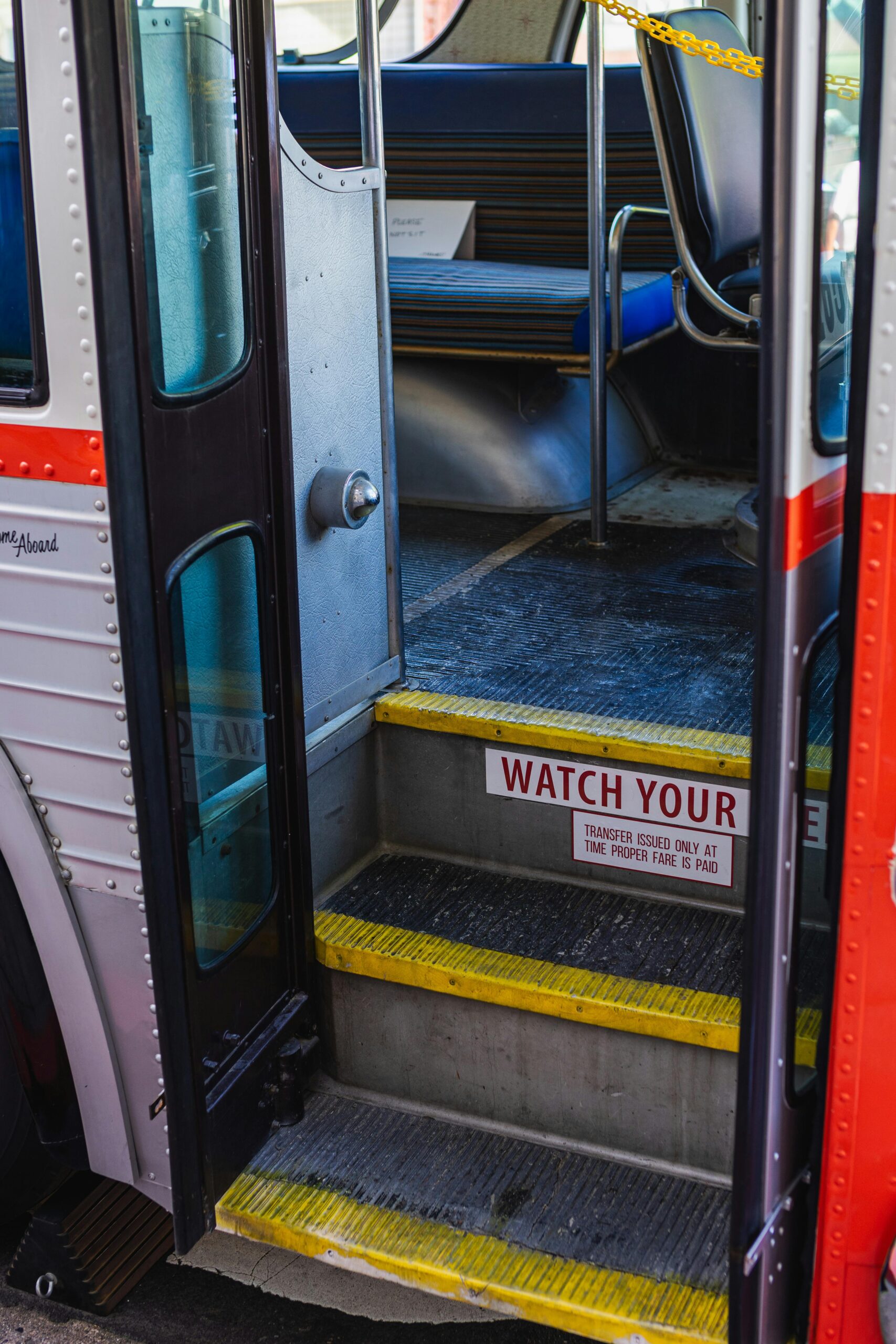 View of a public transportation bus interior focusing on open doors and steps with warning signs.